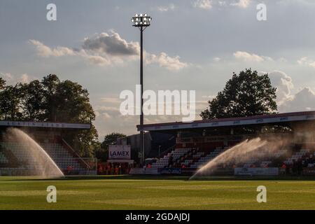 Football pitch at lower league ground at dusk with sprinklers watering the pitch. Stock Photo