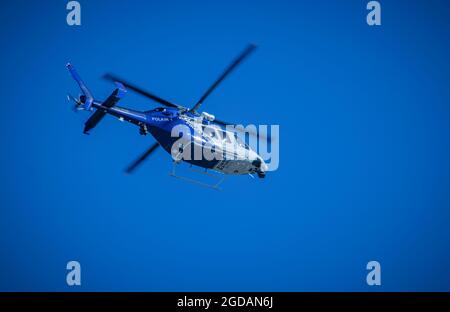 New South Wales Police Force, Polair 1, Police helicopter flying high against a blue sky with motion blurred rotor blades, sun reflecting Stock Photo