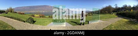 France Haute-Savoie Annecy : Un homme en noir telephone sur un chemin au bord du lac Stock Photo