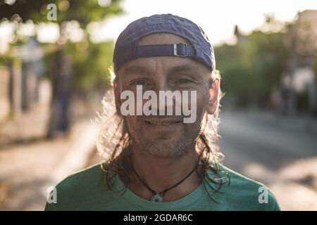 Portrait of mature man with grey hair in cap. Sunlight background. Looking at camera with copy space. . High quality photo Stock Photo