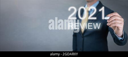 businessman writes 2021 review words. businessman writes 2021 results on virtual screen. economic indicators, overcoming the crisis and economic recov Stock Photo