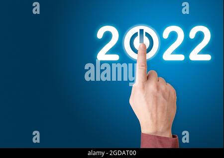 hand presses the start button for 2022. Happy New Year 2022. New Year New You, resolution, change, goal, vision, innovation and planning concept. Begi Stock Photo
