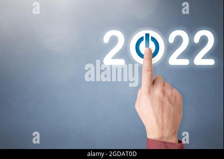 Finger pressing blue start 2022 button on virtual interface on gray background with copy space for text. Concept of new year. Businessman pressing 202 Stock Photo