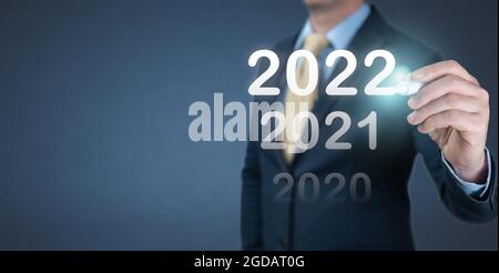 hand businessman writing 2022 number on virtual screen. Business and Technology target set goals and achievement in 2022 new year resolution, planning Stock Photo