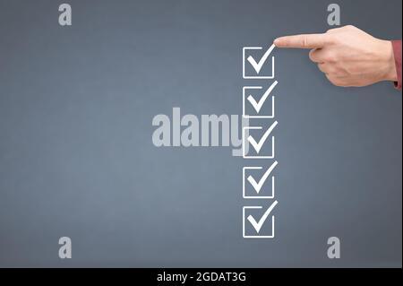 hand ticking checkboxes with marker pen on checklist or to-do list with copy space. gray background. Hands check all the check box. to do list mockup. Stock Photo