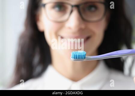 Young woman with glasses holding toothbrush closeup Stock Photo