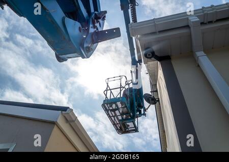 Worker on a aerial access platform, cherry picker, cleaning house. Stock Photo