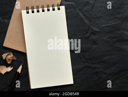 Open Blank Spiral Notebook with Black Pencil and Pencil Shavings on Black Background, Copy Space for text, Flat Lay Concept. Stock Photo