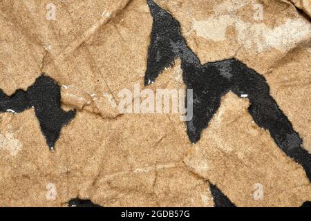 Wet Torn Brown Paper on Black background. Stock Photo