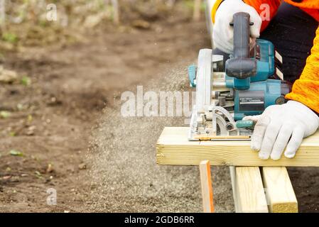 hand circular saw, carpenter sawing boards with a hand-held circular saw in the street Stock Photo