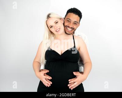 Mixed race father-to-be  holding his caucasian pregnant wife's belly Stock Photo