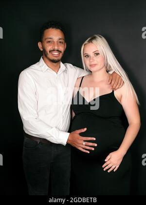 Mixed race father-to-be  holding his caucasian pregnant wife's belly Stock Photo