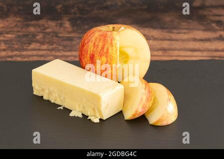 A sliced Apple and some cheddar cheese on a black serving slate board. Stock Photo