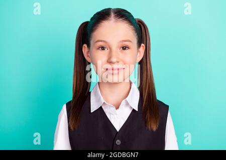 Photo portrait little girl with tails smiling in uniform isolated pastel teal color background Stock Photo