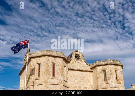 Detail of the historic prison in Fremantle, Western Australia, with the Australian flag blowing in the wind against a dramatic sky Stock Photo