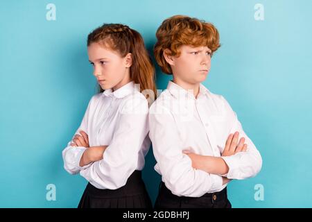 Portrait of two attractive gloomy moody kids folded arms conflict quarrel isolated over bright blue color background Stock Photo
