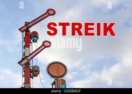 Railroad signal and German text Streik, meaning strike, against a blue sky with clouds, copy space Stock Photo