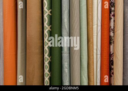 A fragment of rounded ends at the edges hangs vertically in a row of fabric curtains in green, gray, beige, orange and brown shades. Natural textile b Stock Photo