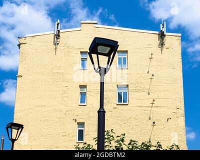 street lantern, yellow painted wall of old brick house and blue sky with white clouds in Moscow city on sunny summer day Stock Photo