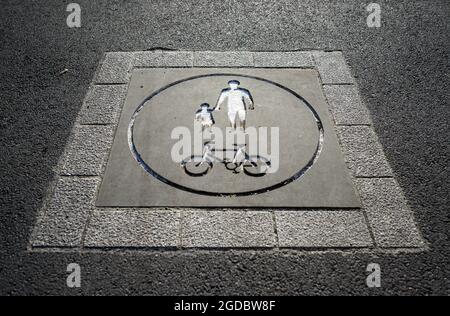 Sign set in a path indicating that it is a shared footpath and cycle path. The sign shows a symbol of an adult with a child and a symbol of a bicycle. Stock Photo