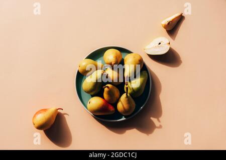 Fresh ripe pears on green plate on beige background. Healthy vegan food. Top view, flat lay. Stock Photo