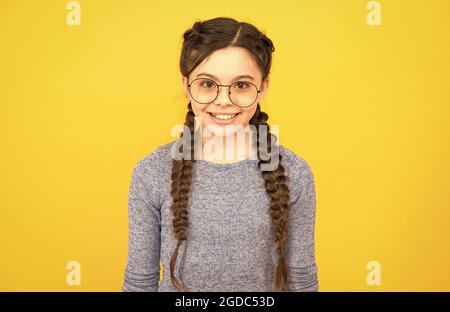 Giving the girl confidence and precision. Happy girl wear glasses yellow background. Fashion look of baby girl. Little girl in casual style. Hair Stock Photo