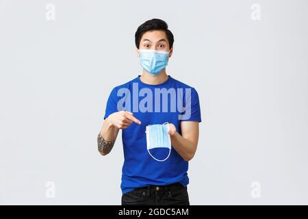 Different emotions, social distancing, quarantine on coronavirus and lifestyle concept. Excited asian man in protective equipment, pointing finger at Stock Photo