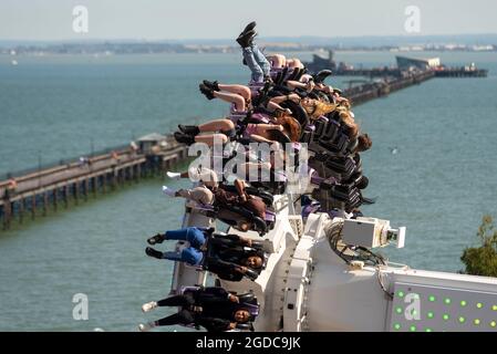 Thrill riders on Axis ride on seafront theme park of Southend on Sea, Essex, UK, as England opens up after lockdown. Diverse ethnicity youngsters Stock Photo