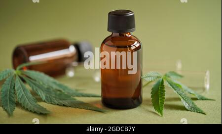 Medical Marijuana Cannabis oil extract in bottle green hemp leaves and glass test tubes on a green background.Close-up glass bottles with CBD oil, THC Stock Photo