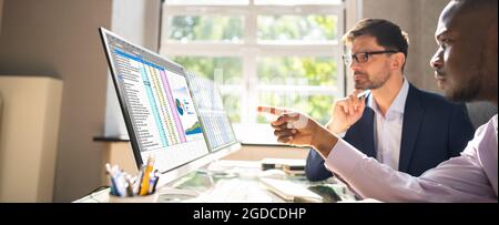 People Working With Spreadsheet Data On Computer Monitor Stock Photo