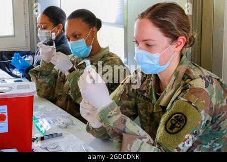 U.S. Army 1st Lt. Abigail Santora, right , a medical surgical nurse at Carl R. Darnall Army Medical Center, Fort Hood, Texas, and 2nd Lt. Sharice Jones, center, a medical surgical nurse at Brooke Army Medical Center, Fort Sam Houston, Texas, work alongside Federal Emergency Management Agency (FEMA) volunteer medical staff to prepare COVID-19 vaccines at the Fair Park COVID-19 Community Vaccination Centers  in, Dallas,  on March 2, 2021. U.S. Army Medical Command Soldiers deployed to Dallas to provide support to FEMA COVID-19 Community Vaccination Centers. U.S. Northern Command, through U.S. Ar Stock Photo