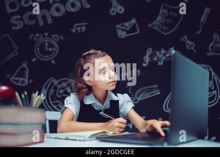 Happy teen school student studying with laptop books doing online research homework assignment, white Caucasian teenage girl using computer Stock Photo