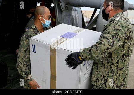 NAVAL AIR STATION SIGONELLA, ITALY (March 10, 2021) Chief Logistics Specialist Wilder Fermangomez, left, and Logistics Specialist 1st Class Rolando Sol, both assigned to Defense Logistics Agency Distribution Sigonella, load a box of COVID-19 vaccines onto a MH-60S Sea Hawk helicopter, assigned to the Helicopter Sea Combat Squadron (HSC) 7, for transportation to the Nimitz-class aircraft carrier USS Dwight D. Eisenhower (CVN 69) from Naval Air Station (NAS) Sigonella, March 10, 2021. NAS Sigonella’s strategic location enables U.S., allied, and partner nation forces to deploy and respond as requ Stock Photo