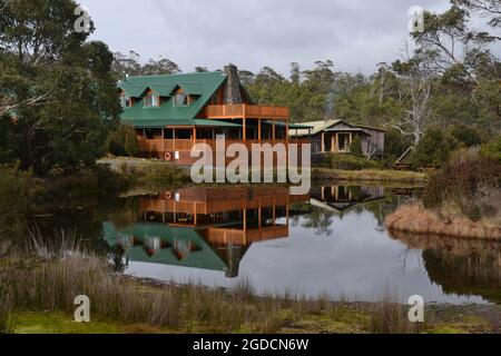 Green roof wooden wilderness lodge reflected across a pond or lake at Cradle Mountain in Tasmania Stock Photo