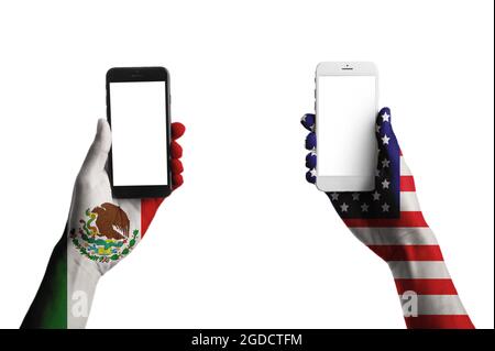 Hands painted in colors of Mexican and USA flags holding mobile phones on white background Stock Photo