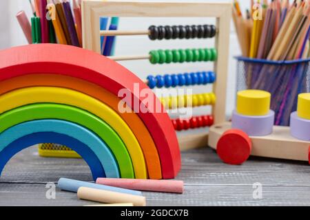 Multicolored Wooden rainbow toy, sorter, pencils, blocks on wooden table. Back to school, games for kindergarten, preschool education. Stock Photo