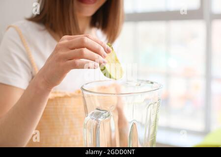 Young woman preparing healthy green smoothie in kitchen, closeup Stock Photo