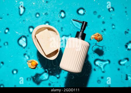 Bottle of cosmetic product, soap and berries in water on color background Stock Photo