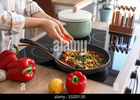 Woman frying vegetables in kitchen Stock Photo