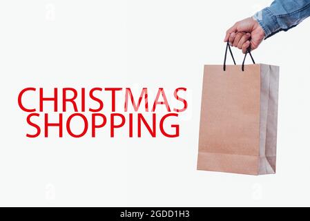 Closeup of a man's hand with a shopping bag and the text Christmas shopping Stock Photo