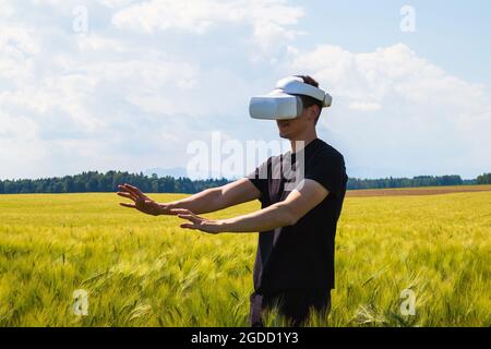 Man using virtual reality glasses outside in nature on a wheat farming field. Stock Photo