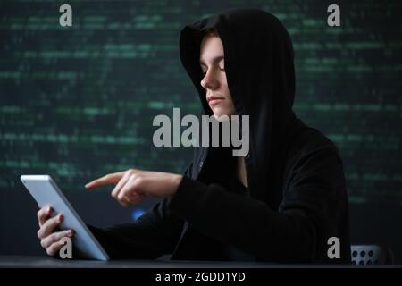 Hacker with tablet computer on dark background Stock Photo