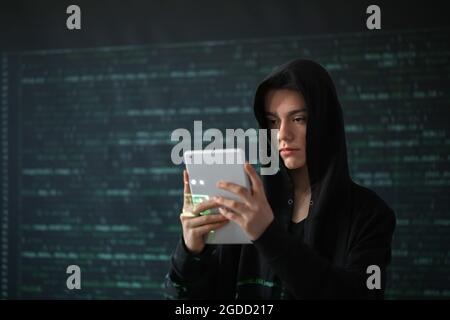 Hacker with tablet computer on dark background Stock Photo