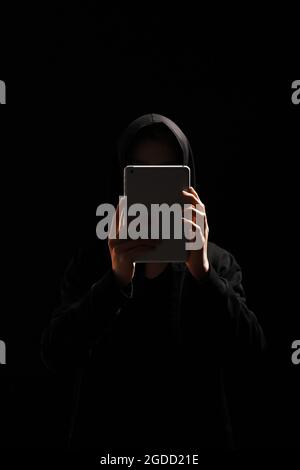Hacker with tablet computer on dark background Stock Photo