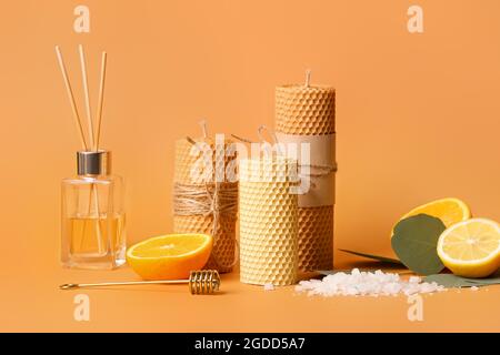 Composition with handmade wax candles, reed diffuser and fruits on color background Stock Photo