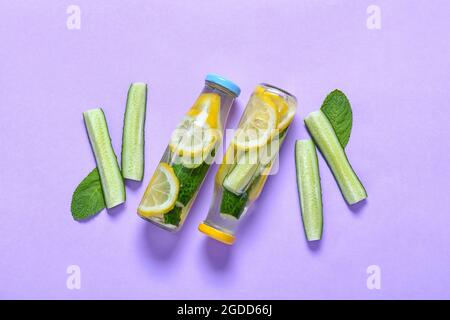 Bottles with cucumber lemonade on color background Stock Photo