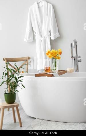 Beautiful daffodils and cup of tea in bathroom Stock Photo