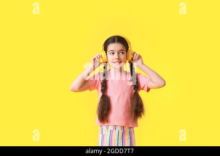 Cute little girl listening to music on color background Stock Photo