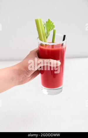 Woman holding glass of bloody mary cocktail on light background Stock Photo