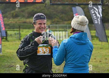 REEFTON, NEW ZEALAND, AUGUST 7, 2021; Competitor Wayne Coutts receives his medal for completing the 10km section of the Red Cross Resilience Ultra end Stock Photo